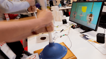 image of arms holding plunger next to monitor with virtual toilet